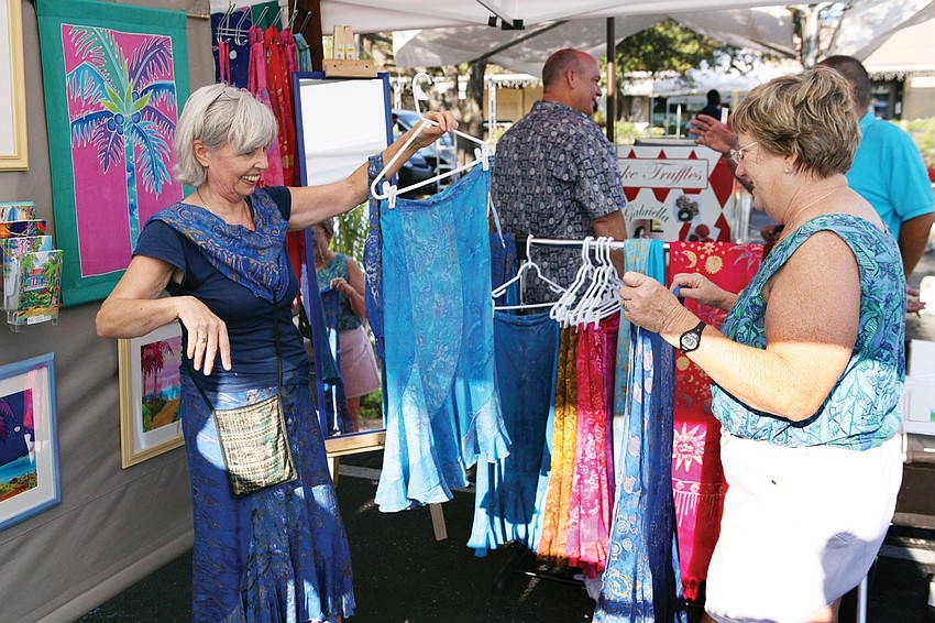 Rita Van Gorder shows the difference between skirts to Dottie Schell, Sept. 1 at the Siesta Key Farmers Market.