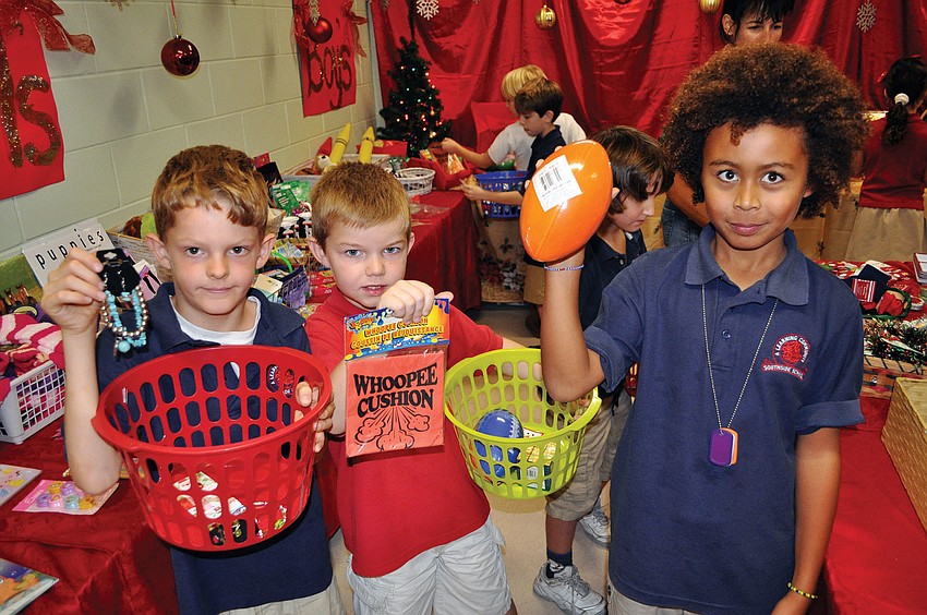 Seven-year-olds David Huber, Luke Fowler and Malakai Stears show their selections from the Holiday House, Dec. 4, at Southside Elementary School.