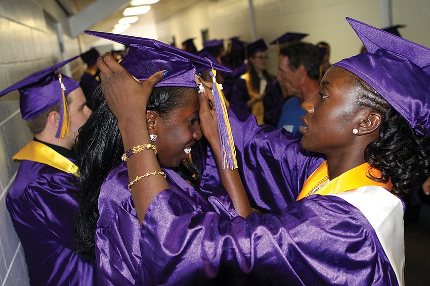 Booker High School's Cherlina Polynice helped Akira Peterson put on her cap prior to graduation.