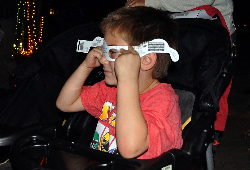Brody Catanzarite, 4, looks through his â€œholiday specsâ€ that changed the lights from round into snowflakes.
