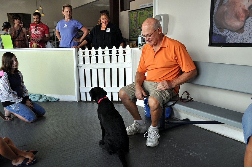 Puppy trainer Dennis Quinn sits with Tangerine, a 5-month-old black lab.