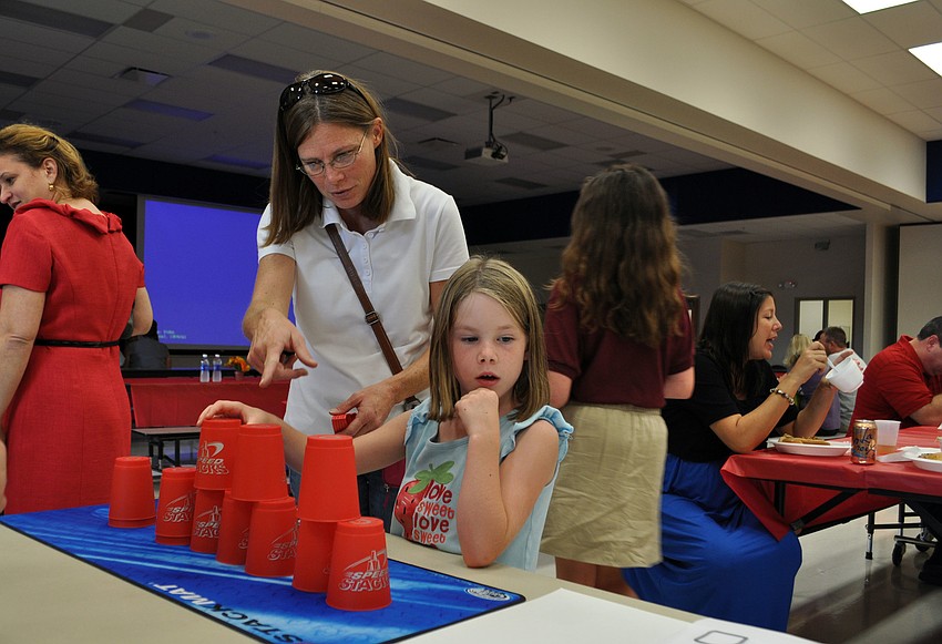 Trisha Mann watches as Alyssa Micallef stacks cups.