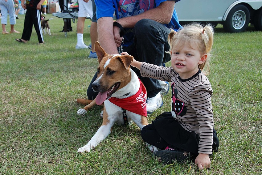 Charley Roman, 2, smiles for a picture while playing with her dog.