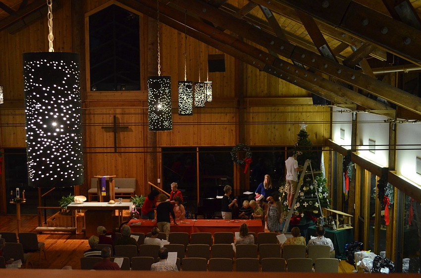Children decorate the Christmas tree as parish members sing Christmas songs.