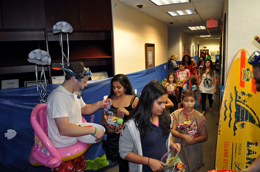 The girls get candy from Merrill Lynch employees Wednesday, Oct. 31, inside their office.
