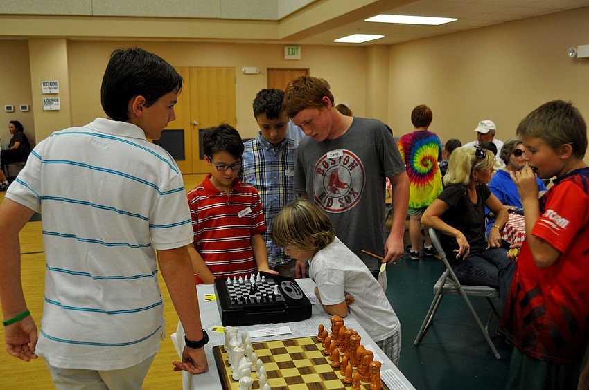 Students examine display chessboards.