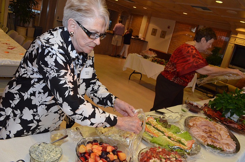 Irene Bier uncovers food for the party.