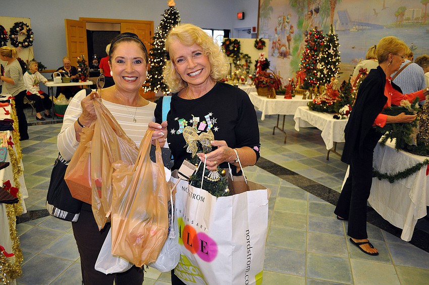Jeanne Kozlowski and Fran Hall show off all the bags full of items they bought at the holiday bazaar.