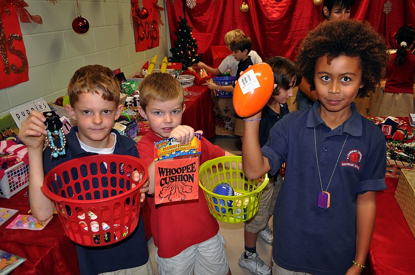 David Huber, 7, Luke Fowler, 7, and Malakai Stears, 7, show off some of the gifts they were planning on buying at the Holiday House.