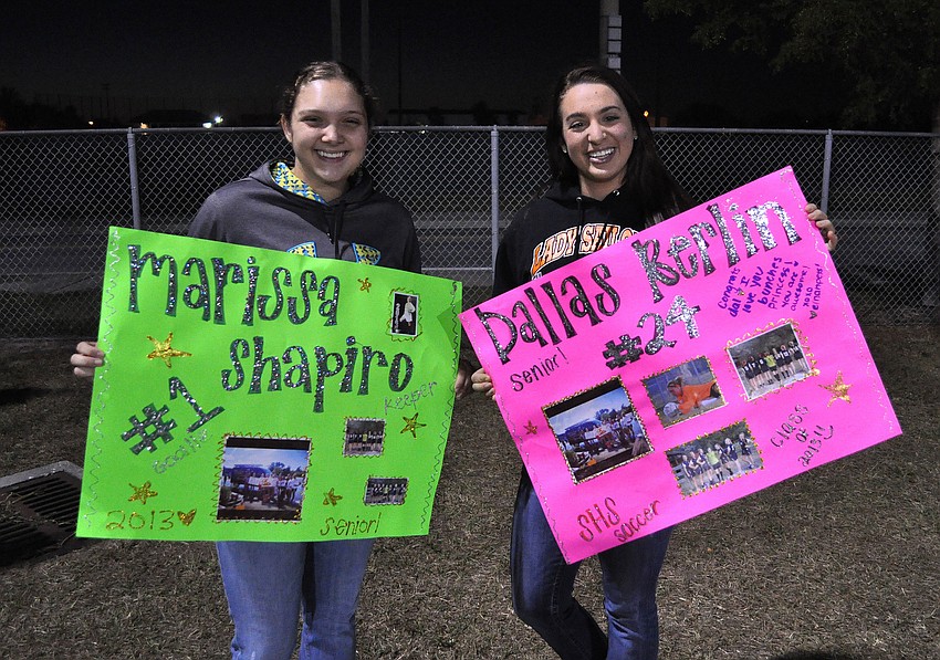 Shelby Thorpe and Stephanie Muscati cheer on their friends with homemade signs Wednesday, Dec. 19, at Sarasota High School.