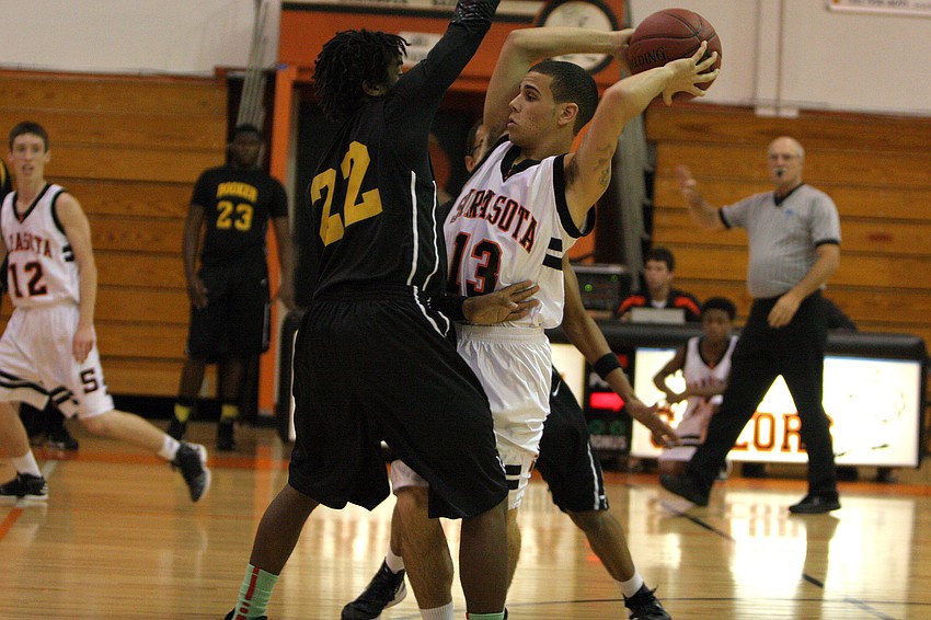 Sarasota High Schoolâ€™s Justin Robbins, No. 13, looks to pass to one of his teammates while being guard by Booker High Schoolâ€™s Rashad Jones, No. 22.