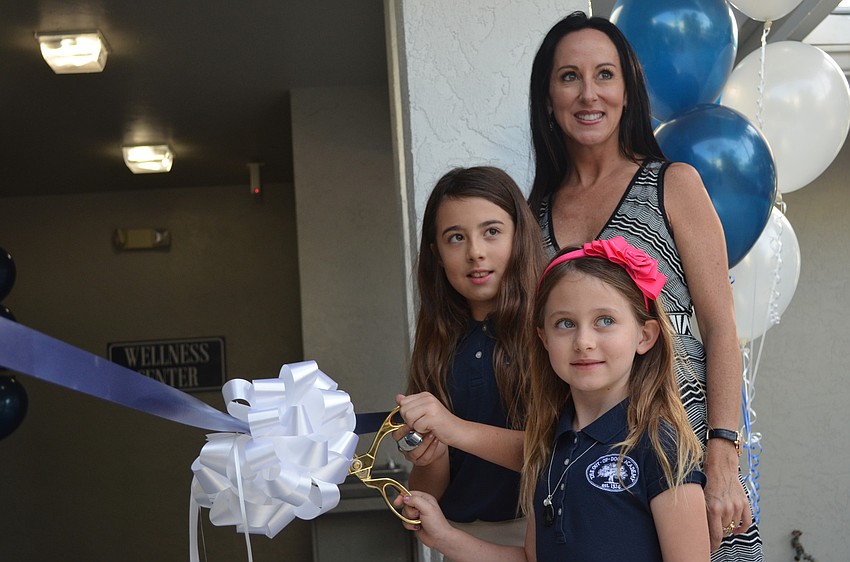 Lexie and Gabby Kozel cut the ribbon to the new Wellness Center as their mother Ashley watches.