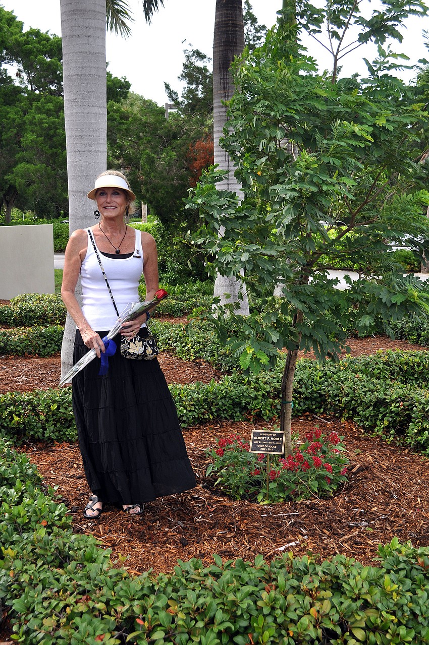 Leslie Hogle poses by the cassia fistula tree that was planted in honor of her late husband Al Hogle.
