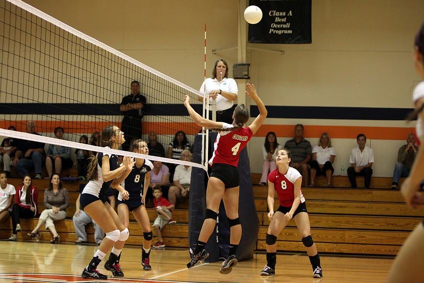 Kelly Firek, No. 4, gets ready to spike the ball as Gabriella Costa, No. 3, and Lauren Maxey, No. 8, prepare at the net.