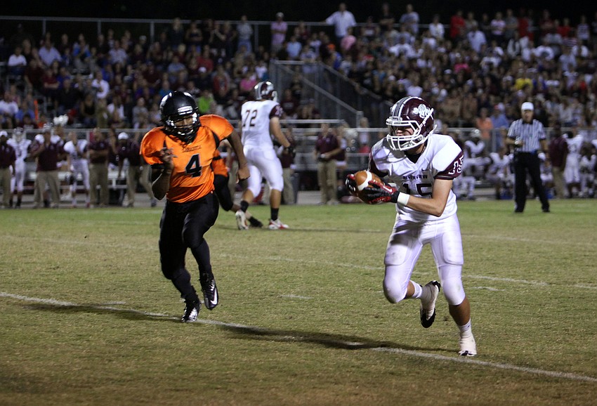 Lex Sayre, No. 15, runs down the field with the ball while Dominique Austin, No. 4, attempts to catch up with him and tackle him.
