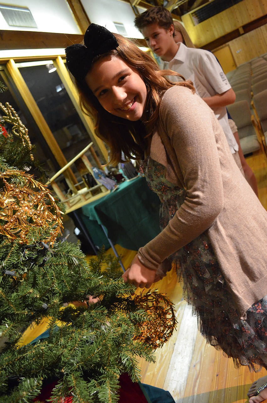 Emma Johnson puts ornaments on the tree.