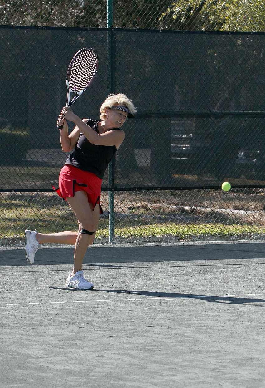 Kathy Hase follows through on her backhand after hitting ball.