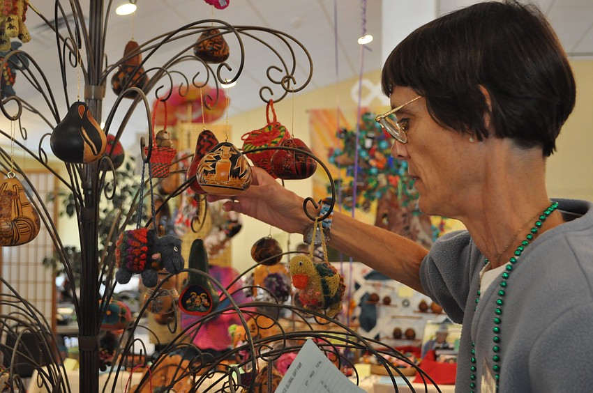 Katherine Johnson looks at a handmade gourd Christmas ornament made in the Andean Mountains of Peru.