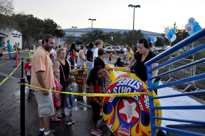 Children stand in line to sled down the ice slide.