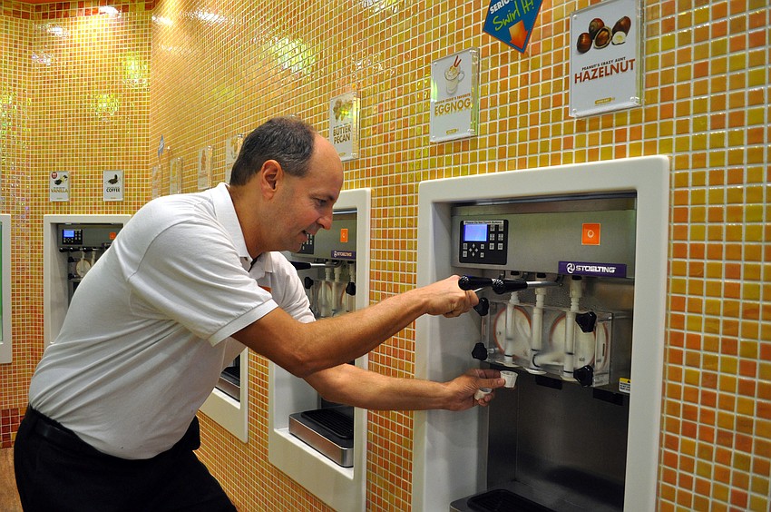 Mike Bess, owner of Orange Leaf Yogurt, fills up a sample cup with some frozen yogurt.
