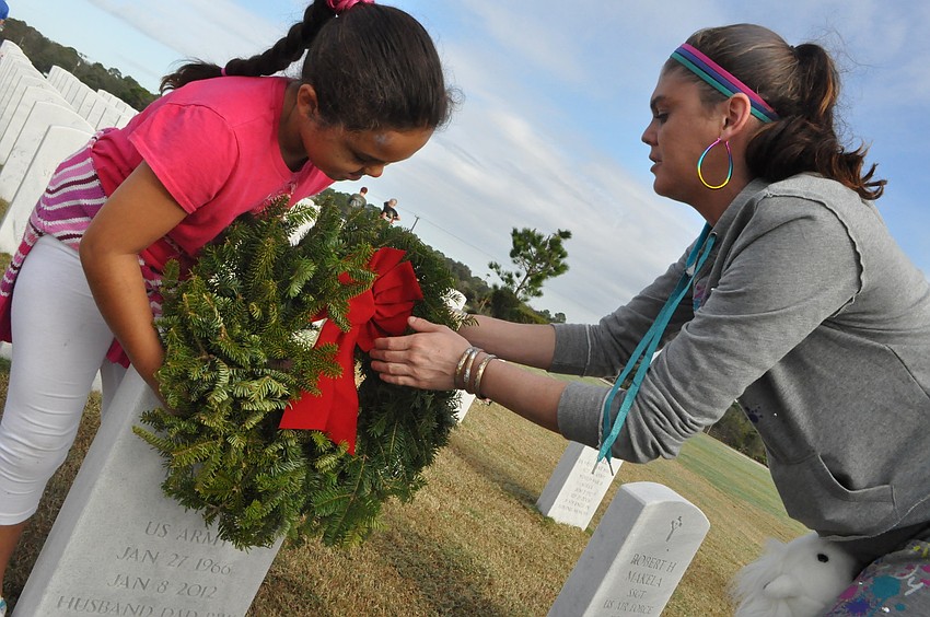 Aaliyah Johnson, 8, puts a wreath on her grandfatherâ€™s grave with her mother Heather.