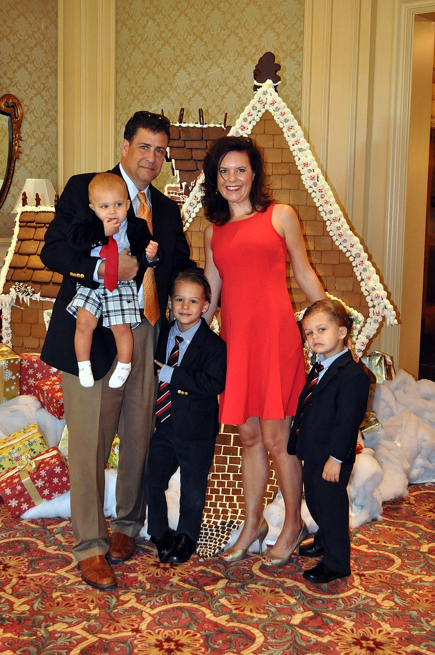 Doug and Shari Phillips pose in front of the large gingerbread house with their sons Parker, 1, Johnathon, 5, and Harrison, 4, Sunday, Dec. 16, at the Breakfast with Santa event at the Ritz Carlton.