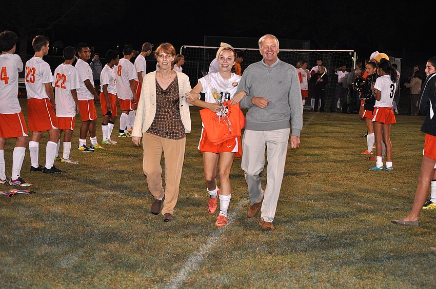 Haley Stuart, No. 19, walks with her parents during Senior Night Wednesday, Dec. 19, at Sarasota High School