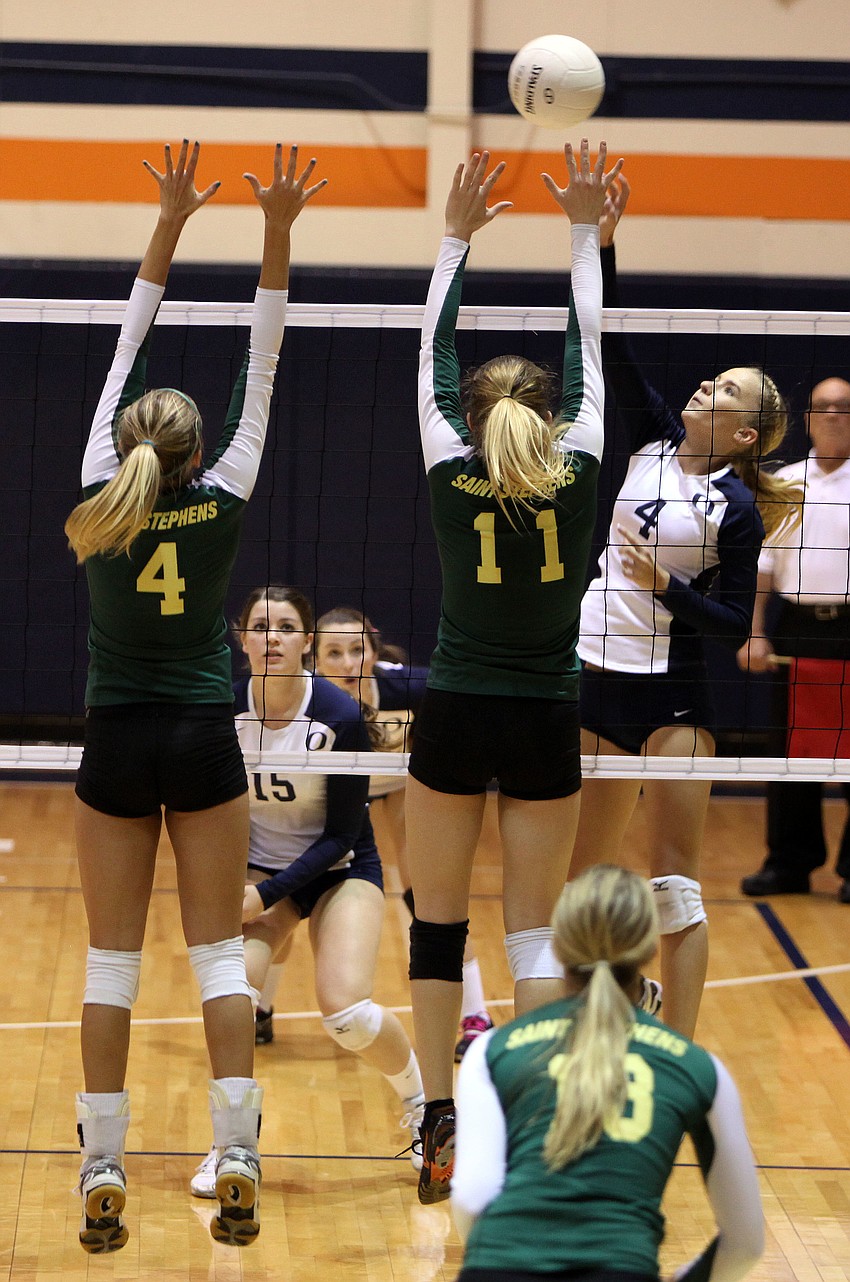 Natalie Buffett, No. 4, spikes the ball at Gabrielle Woodruff, No. 4, Amanda Everhardus, No. 11.