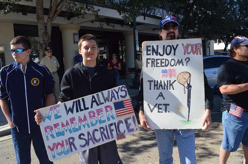 Lucas Wilson and his father Keith hold signs to recognize veterans.