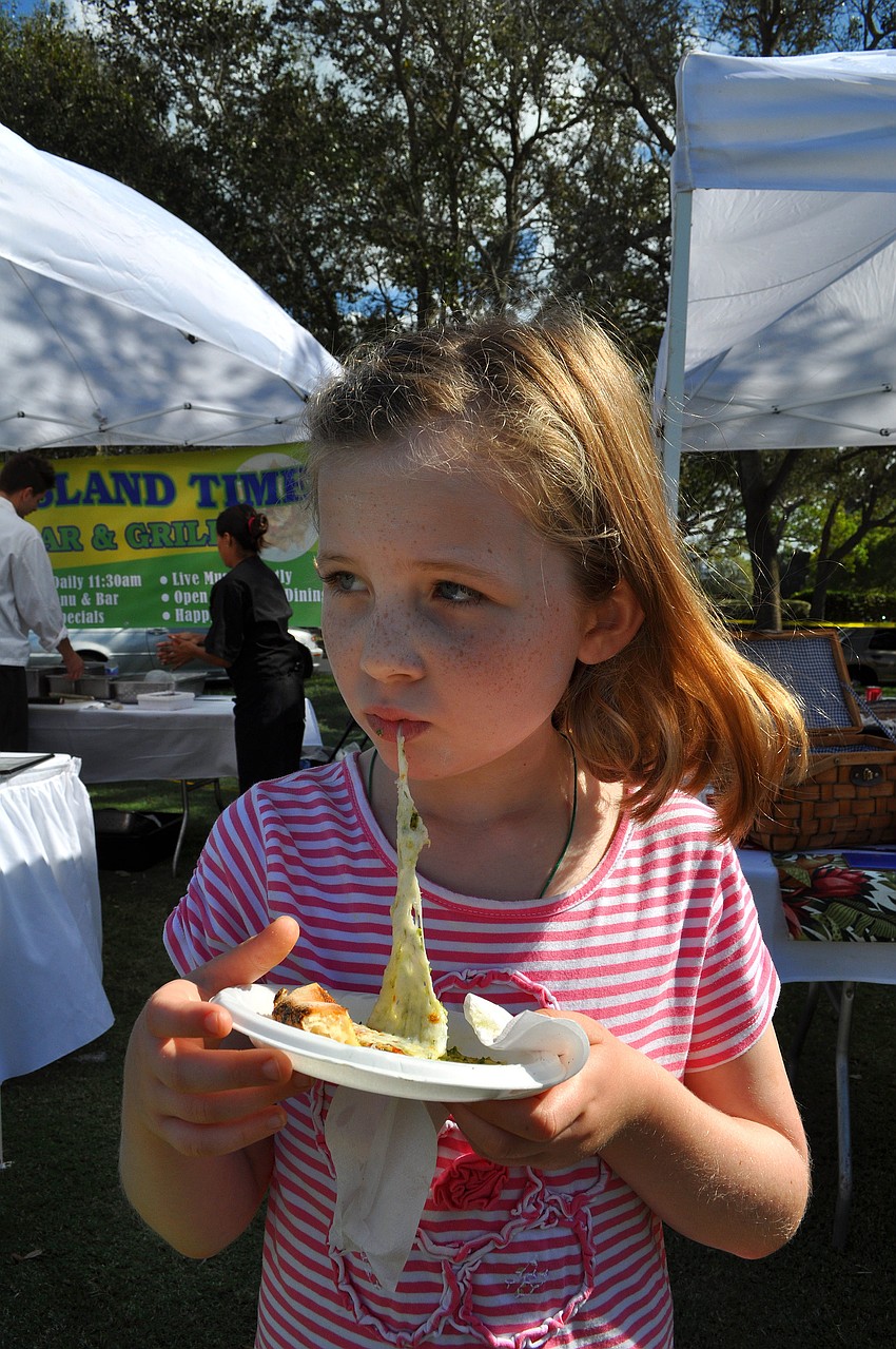 Maddie Cashen, 8, enjoys eating a piece of pizza from The Village Idiot Saturday, Nov. 17, at the Longboat Key Gourmet Lawn Party.