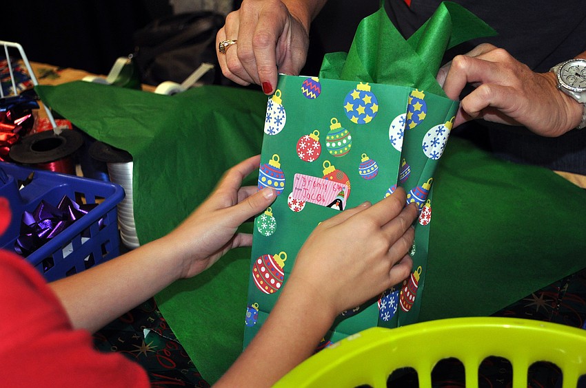 Michelle Matuszak holds up one of Jacob McIntyreâ€™s holiday purchases to let him put the proper sticker on it Tuesday, Dec. 4, at Southside Elementary.