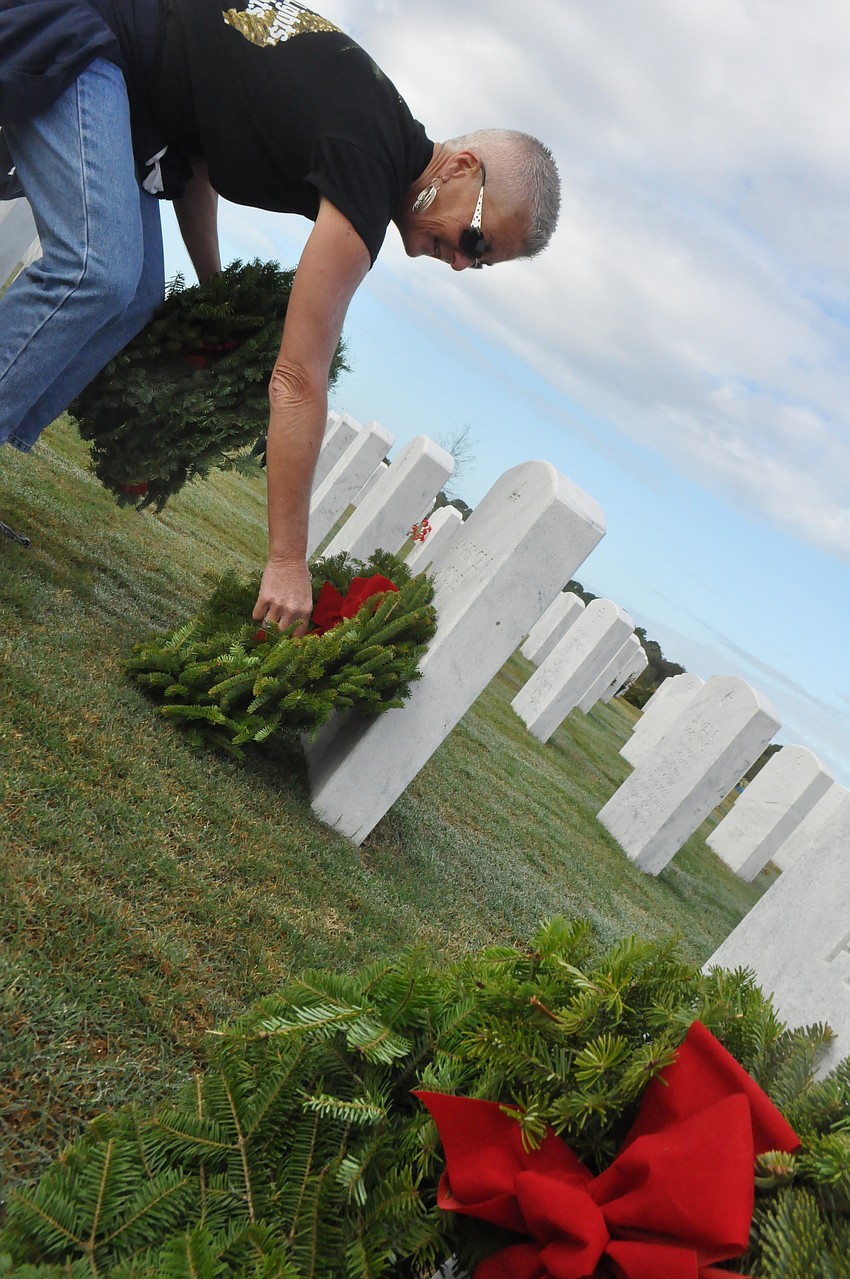 Kathleen Warblow puts a wreath on George Johnsonâ€™s grave, her father.