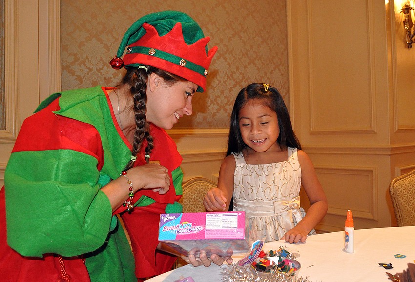 Elf Many helps Mia Albright-Sligar, 5, pick out which candy cane would be perfect for the tail of her candy cane mouse Sunday, Dec. 16, at the Breakfast with Santa event at the Ritz Carlton.
