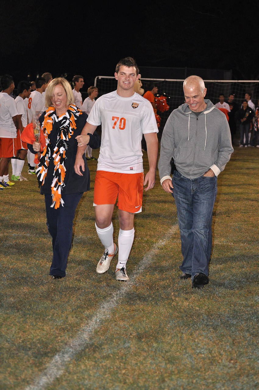 Sarasota High School senior John Finazzo, No. 70, walks during Senior Night with his parents Wednesday, Dec. 19, at Sarasota High School.
