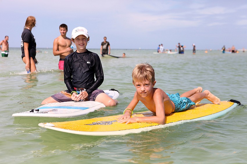 Ben Hershfeld, 11, hangs out on a surfboard next to his brother, Fisher, 7, Saturday, Sept. 15, during Hang 10 for Autism.