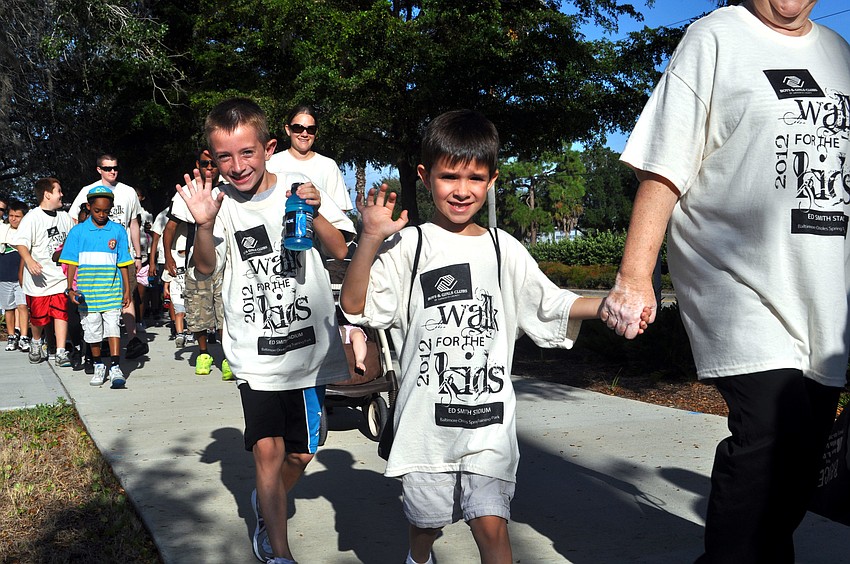 Kids wave as they walk around Ed Smith Stadium
