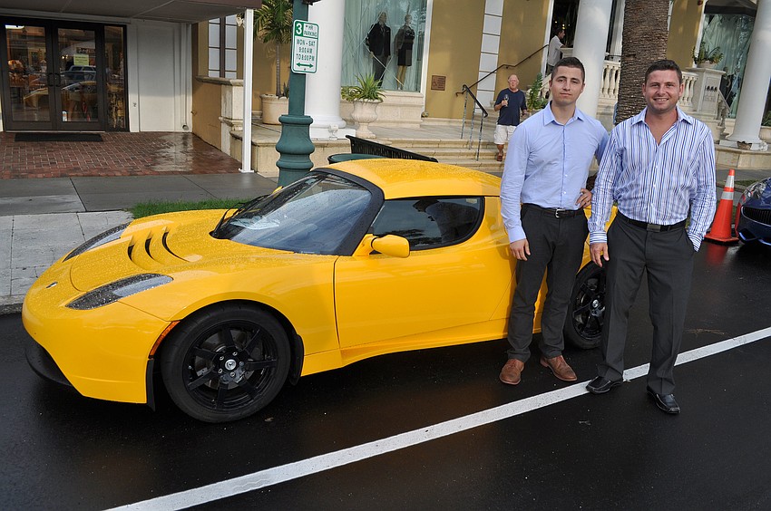 Luke Wells and Jeff Revenaugh pose in front of a Tesla Roadster.