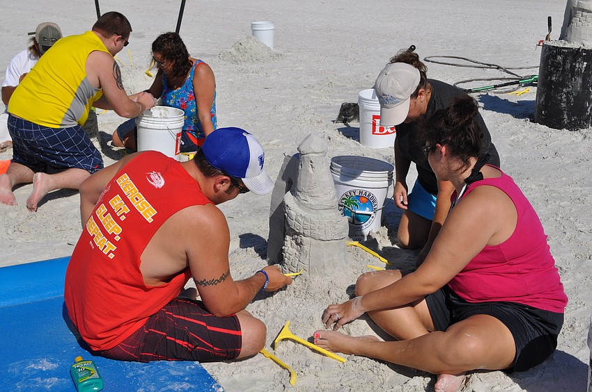 Adam and Elizabeth Rhodus use plastic sculpting tools to add details to their castle, while Libby Bennett coaches the couple.