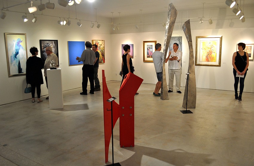 People walk around and look at a variety of different art featured in the Artists Who Made Sarasota Famous II exhibit.