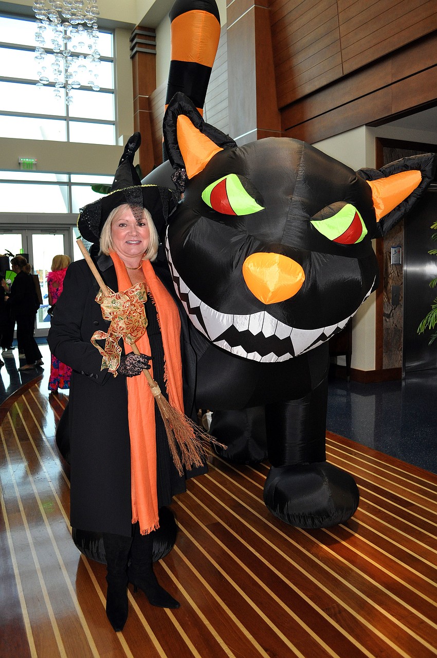 Kathleen Garcia dressed as a witch and posed next to the inflatable, moving, black cat.