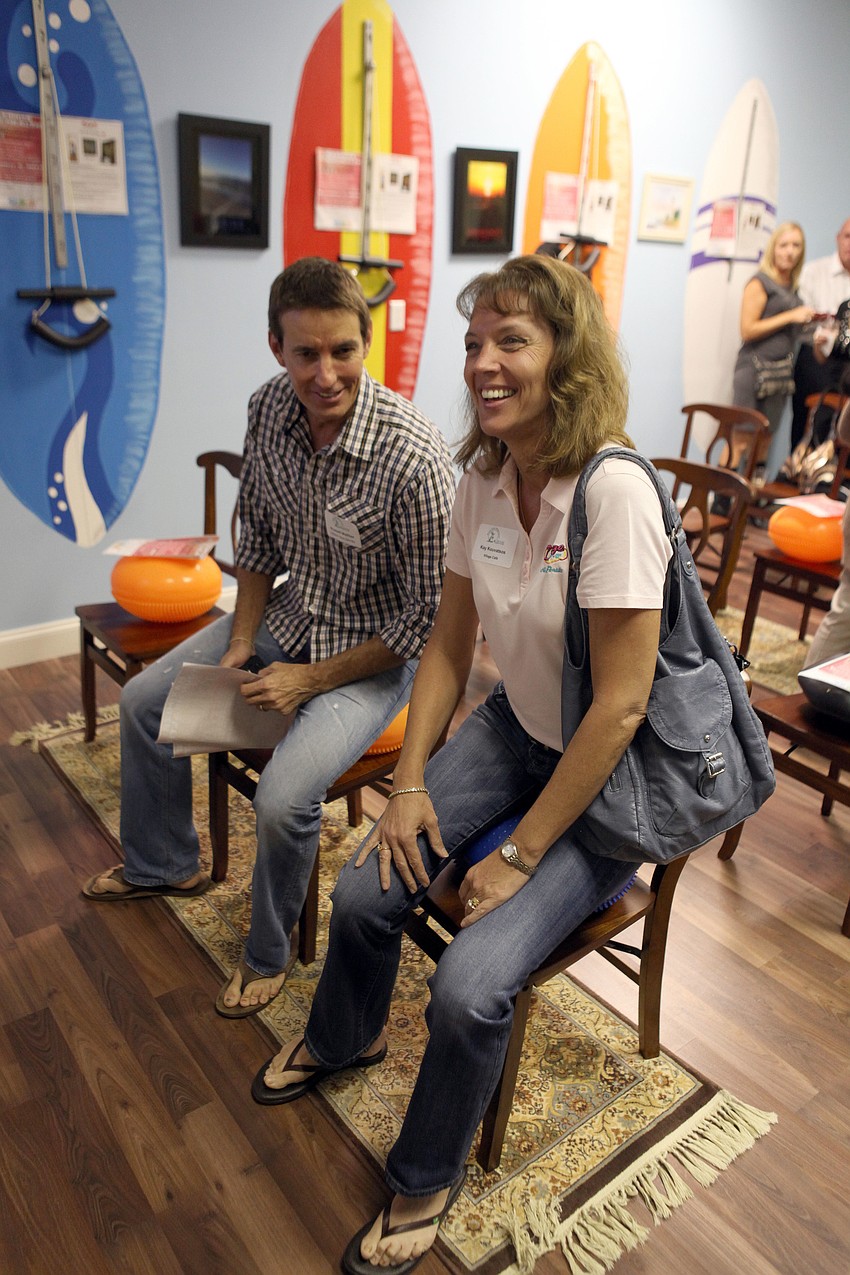 Randall Matthes and Kay Kouvatsos try out some of the equipment at Amazing Life Chiropractic Thursday, Nov. 15, during the Siesta Key Chamber of Commerce Business Card Exchange event.