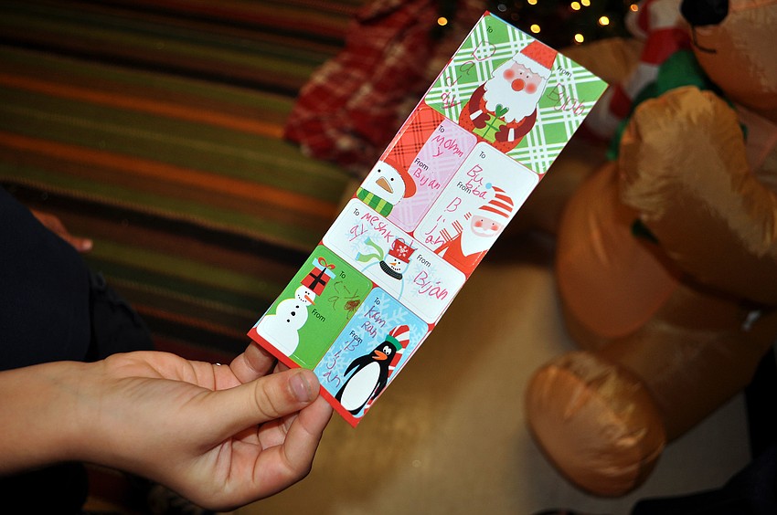 Bijal Molavi, 7, shows off the to and from stickers he wrote out to know who he was going to buy for Tuesday, Dec. 4, at the Holiday House.