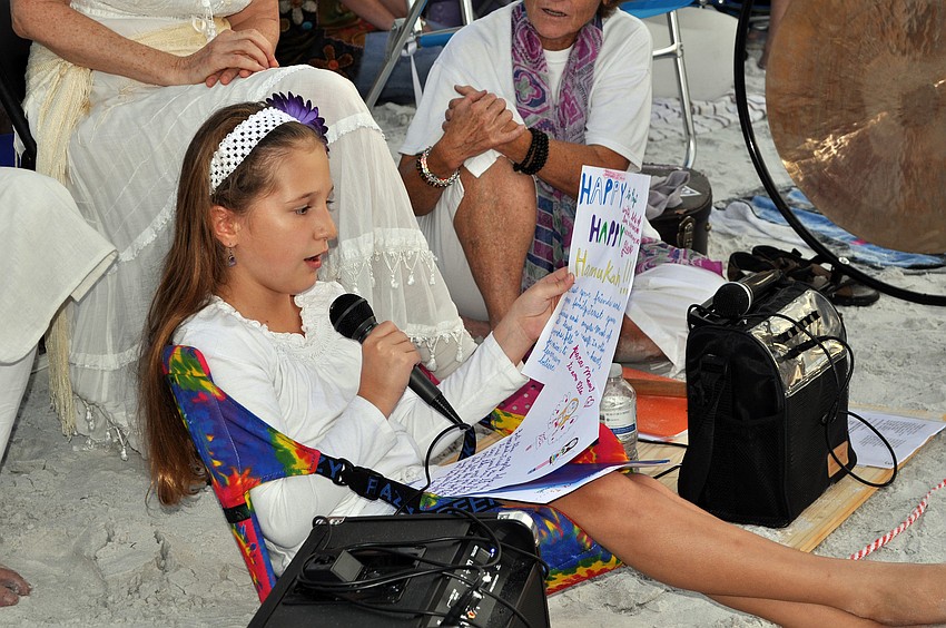 Ella Mirman reads a prayer for the world that she wrote herself to the crowd during the ceremony.