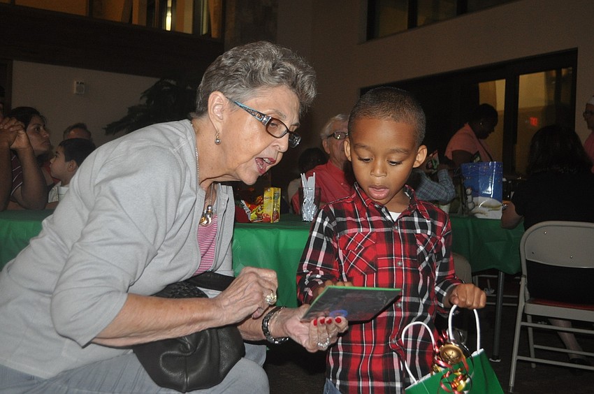 Cassan Johnson, 3, shows reading buddy Jane Anderson the tic tac toe book he received from Santa.