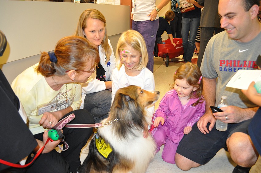 Karen Sundmaker, Kristen Cofer of Sarasota Orthopedics, Avery McCoy and Bella and Jeff Toscano interact with Suki, a therapy dog for the pediatric unit