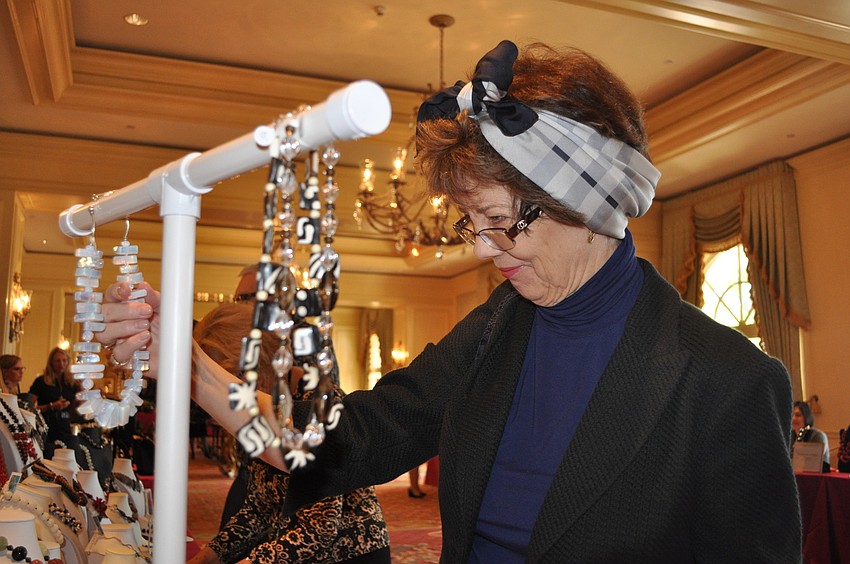 Diane Mott Davidson looks at some of the jewelry at the Artistic Jewelry table.