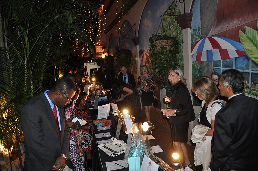 People walk around the tables looking at the items up for auction.