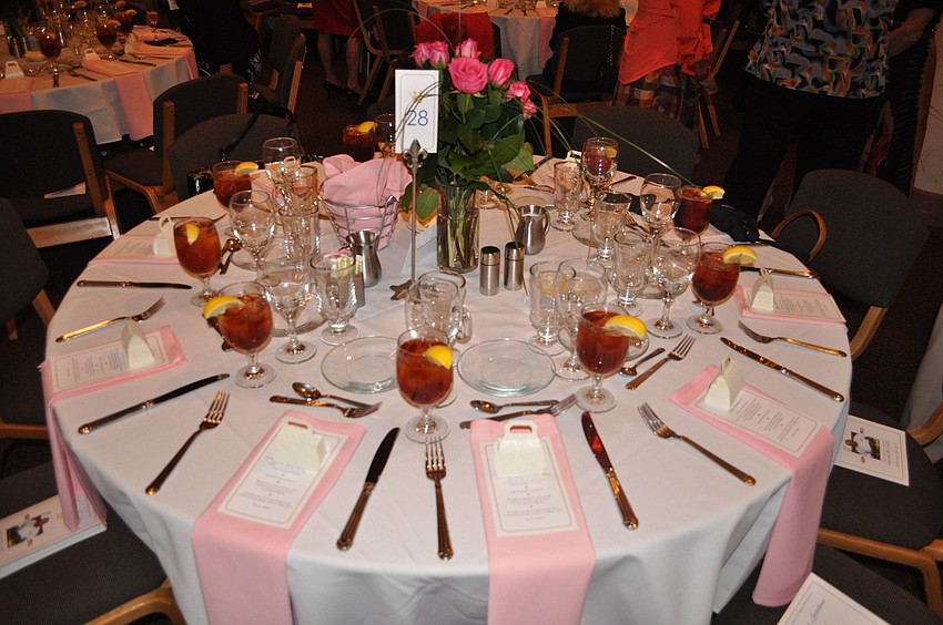The tables all has pink roses in vases as the centerpieces with light pink napkins.