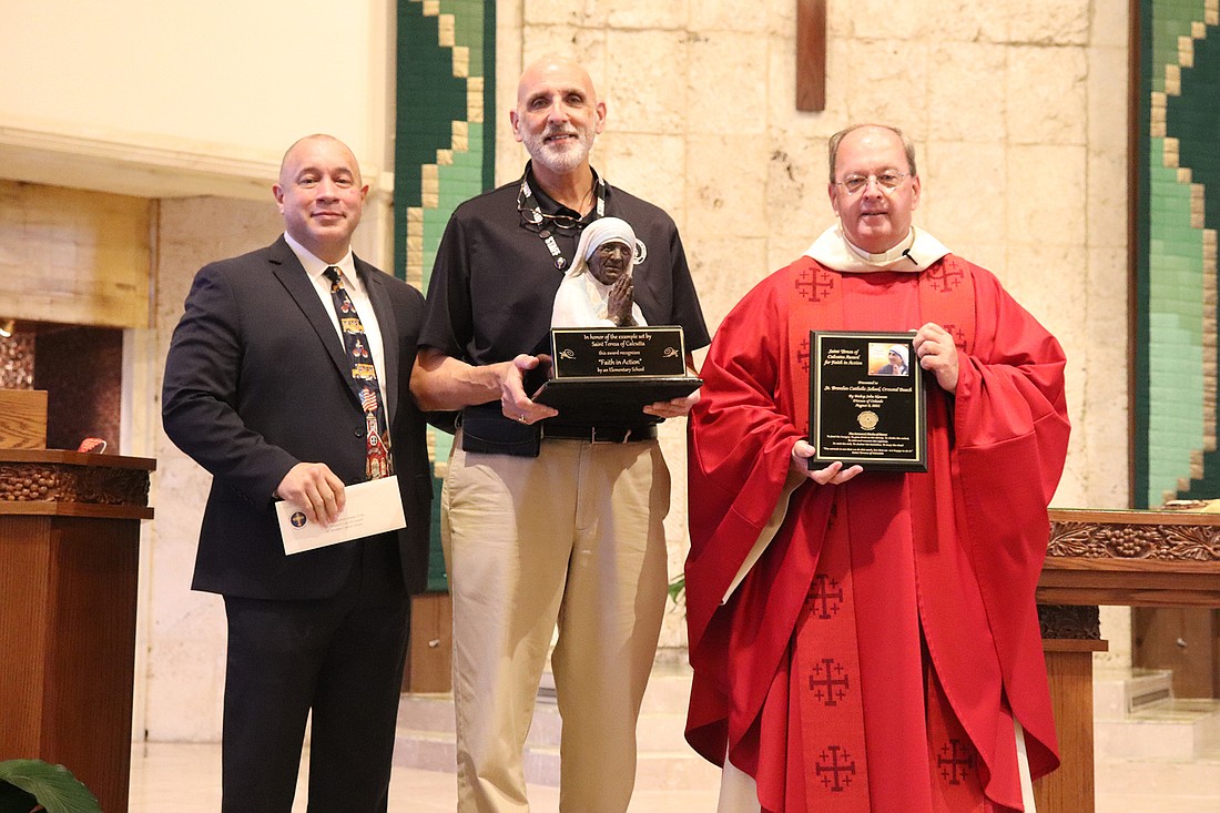 Henry Fortier, secretary of education and superintendent of Catholic Schools at the Diocese of Orlando, presents the award to St. Brendan Catholic School's principal Philip Gorrasi and pastor Friar Thomas Barrett. Courtesy photo