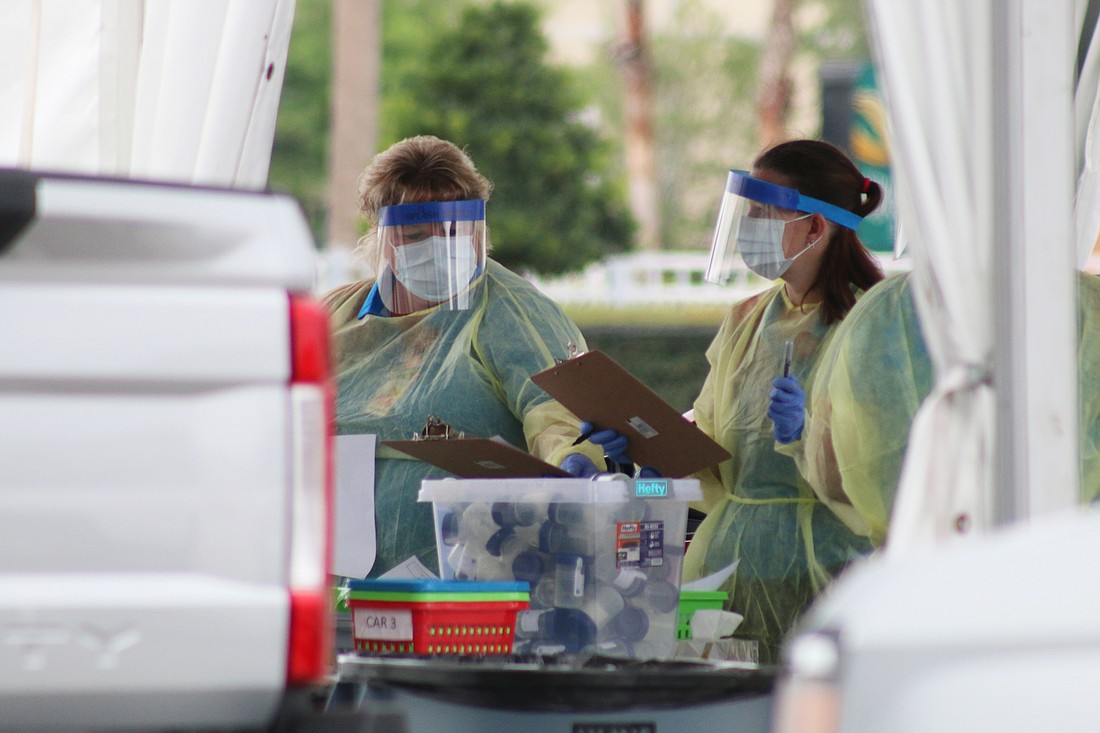 Health care workers test for COVID-19 during a drive-thru site at the Daytona International Speedway in 2020. File photo